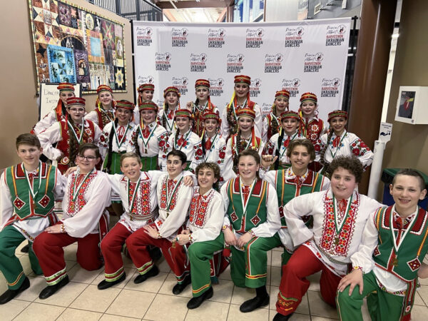A group of children in colorful, traditional costumes pose for a photo. They wear intricate embroidered outfits at Prince Albert Barveenok Ukrainian dancers festival.